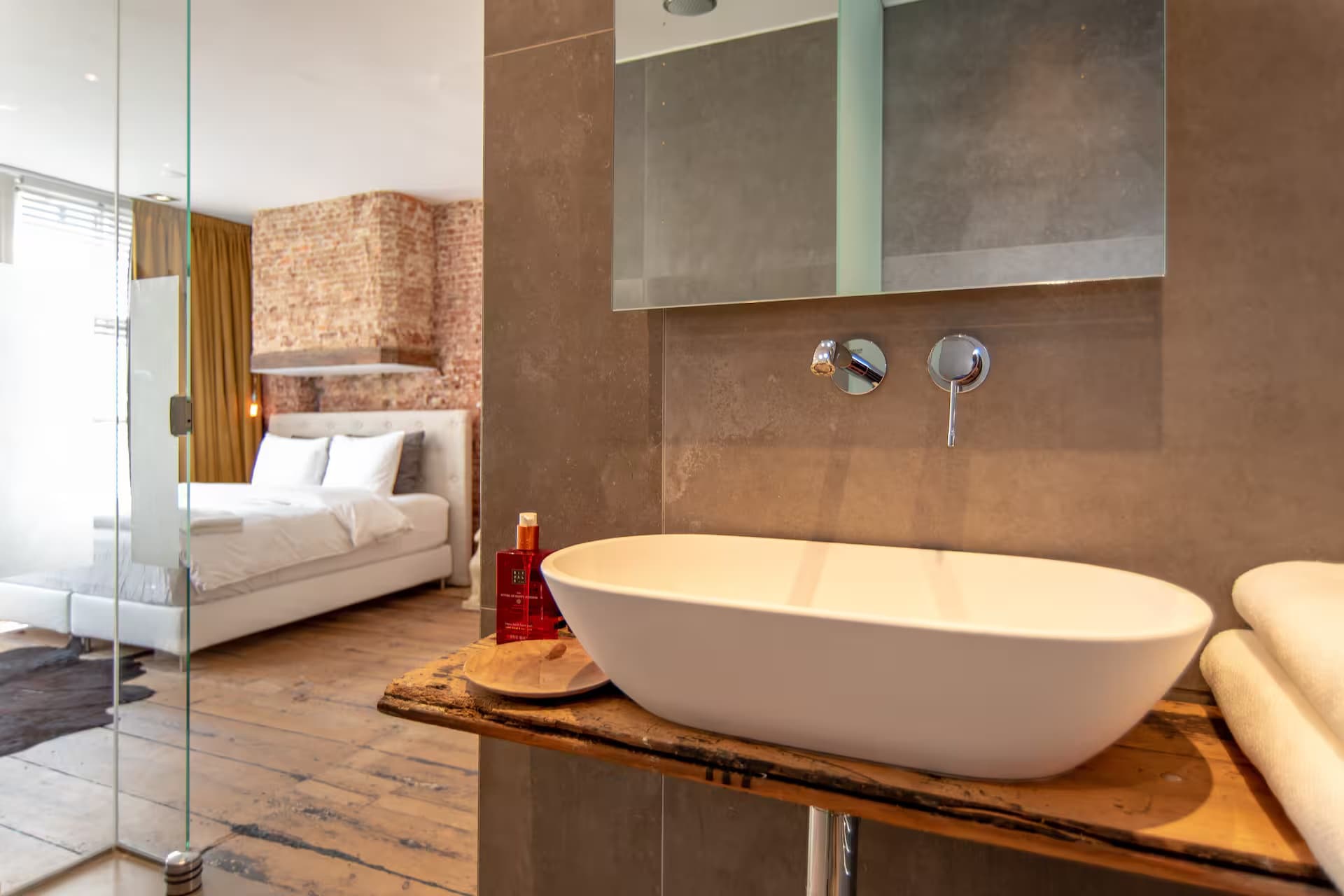 Double Fun — wastafel-detail op ruwhouten plank met chromen kraan en doorzicht naar slaapkamer