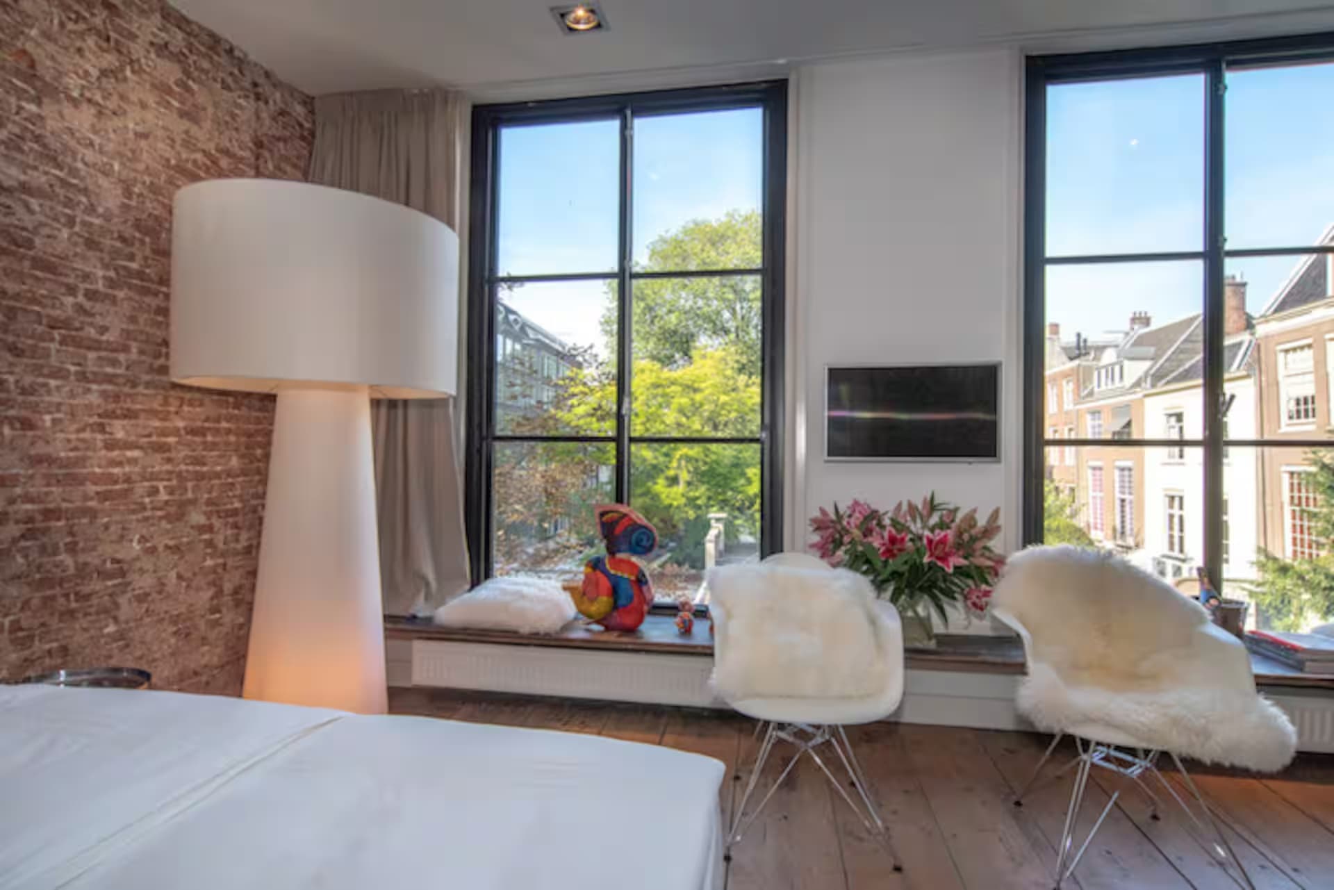 Love Suite — zithoek bij twee ramen met witte fauteuils, schaapsvachten en boeketten op vensterbank